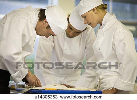 Stock Image - Three chefs filleting a fish. Fotosearch