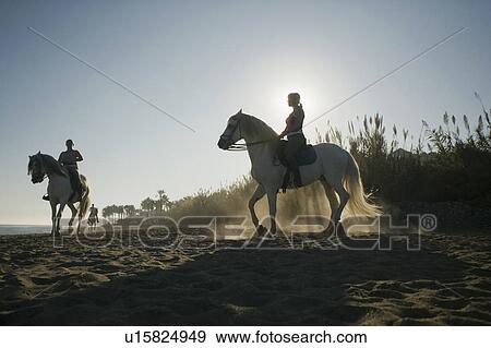 Stock Photo - Three women riding horses on beach. Fotosearch
