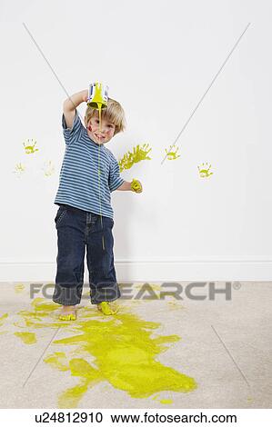 Stock Image - Toddler boy pouring paint onto carpet. Fotosearch