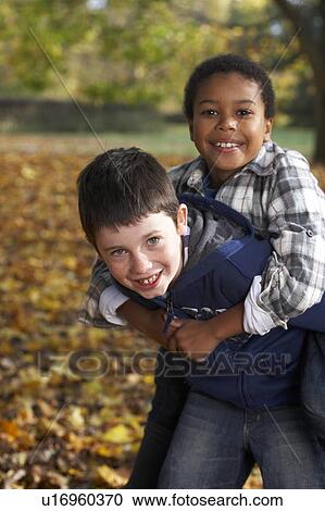 Stock Image - Two boys playing in autumn leaves. Fotosearch