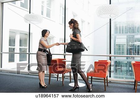 Stock Photo - Two business women shaking hands. Fotosearch