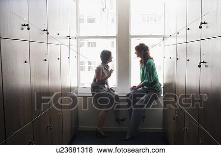 Stock Photo - Two business women talking in a locker. Fotosearch