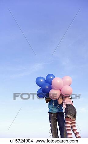 Picture - Two children hidden behind balloons. Fotosearch
