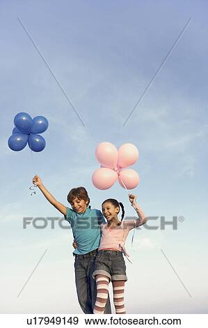 Stock Photo - two children laughing with balloons. Fotosearch