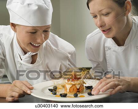 Two female chefs admiring a pudding View Large Photo Image Stock Image - Two female chefs admiring a pudding. Fotosearch