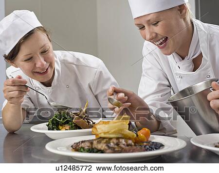 Stock Image - Two female chefs finish some dinners. Fotosearch