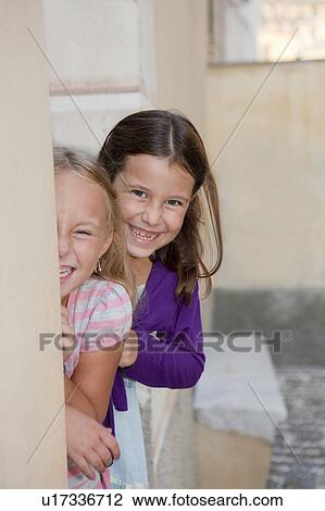 two girls hiding behind wall, laughing View Large Photo Image Stock Image - two girls hiding behind wall, laughing. Fotosearch