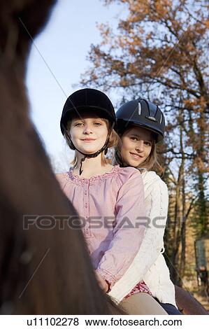 Stock Photo - Two girls on a horseback. Fotosearch