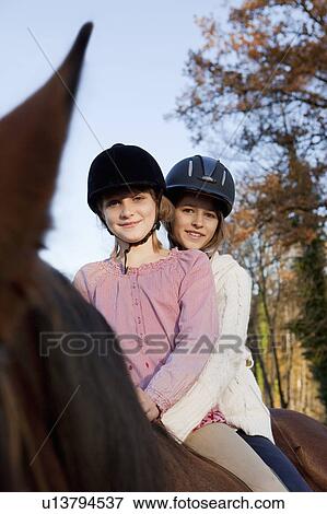 Two girls on a horseback View Large Photo Image Stock Photo - Two girls on a horseback. Fotosearch