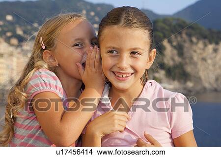Picture - two girls whispering. Fotosearch