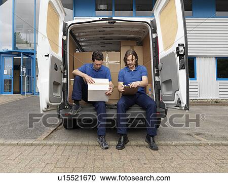 Stock Image - two men delivering boxes in van. Fotosearch