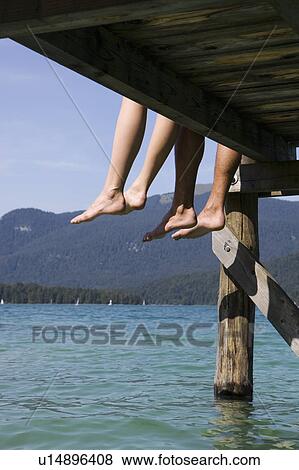 Stock Photo - Two people sitting barefoot by a lake. Fotosearch