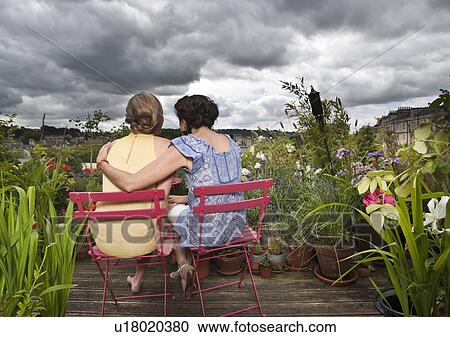 Stock Image - two women hugging on balcony. Fotosearch