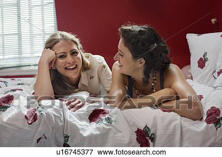 two women laying on bed talking View Large Photo Image Stock Photo - two women laying on bed talking. Fotosearch