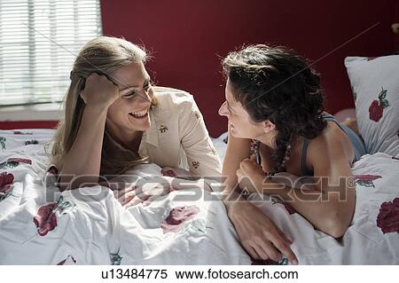 two women laying on bed talking View Large Photo Image Stock Photography - two women laying on bed talking. Fotosearch