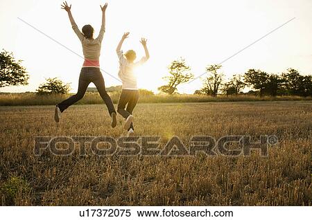 Stock Photography - Two young girls leaping in a corn field. Fotosearch