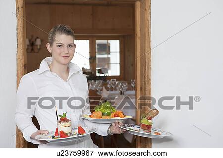 Stock Photo - waitress serving plates, smiling. Fotosearch