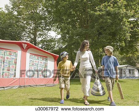 Stock Image - Woman and children walking past tents. Fotosearch