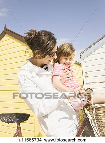 Picture - Woman and girl in front of beach huts. Fotosearch