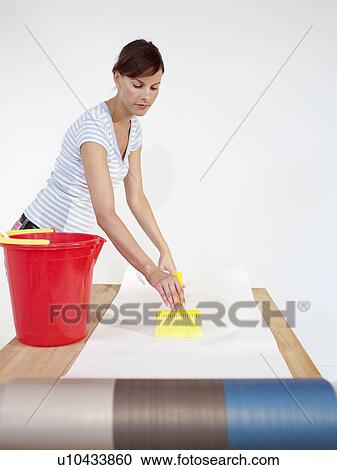 Woman brushing paste onto wallpaper View Large Photo Image Stock Image - Woman brushing paste onto wallpaper. Fotosearch