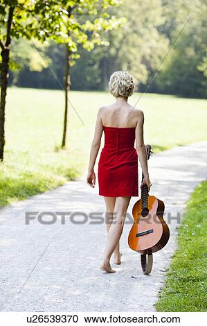 Stock Image - woman carrying guitar. Fotosearch