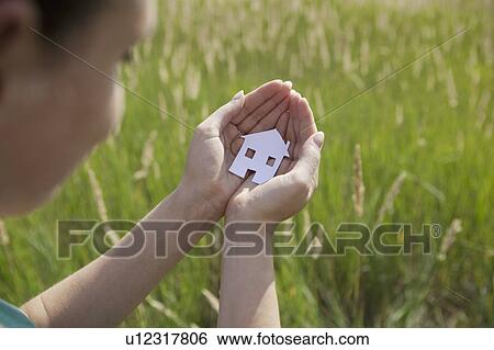 Stock Photograph - Woman cupping cut-out paper house. Fotosearch