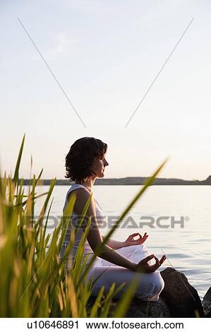 Stock Image - Woman Doing Yoga At Lakeside. Fotosearch