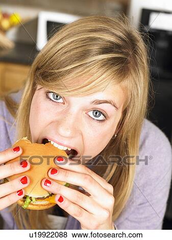 Woman eating an hamburger View Large Photo Image Stock Photo - Woman eating an hamburger. Fotosearch