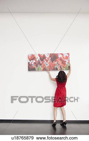 Stock Photo - woman hanging up a picture. Fotosearch