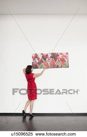 woman hanging up a picture View Large Photo Image Stock Photography - woman hanging up a picture. Fotosearch