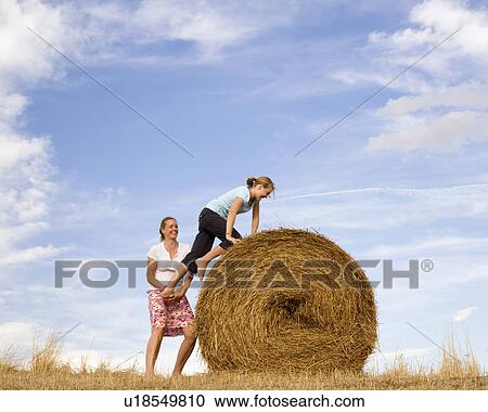 woman helping girl to climb hay bale View Large Photo Image Stock Image - woman helping girl to climb hay bale. Fotosearch