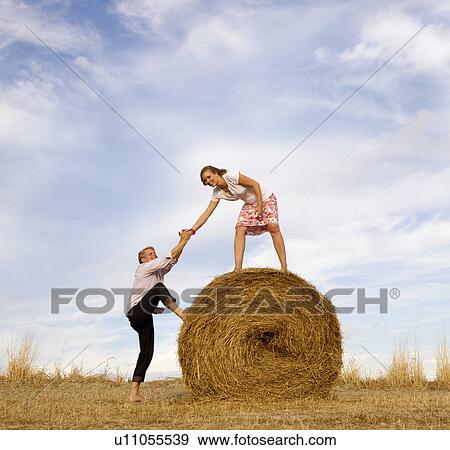 woman helping man to climb hay bale View Large Photo Image Stock Photo - woman helping man to climb hay bale. Fotosearch