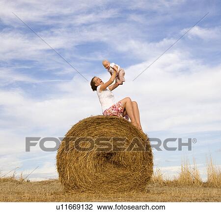 woman holding baby on hay bale View Large Photo Image Stock Image - woman holding baby on hay bale. Fotosearch
