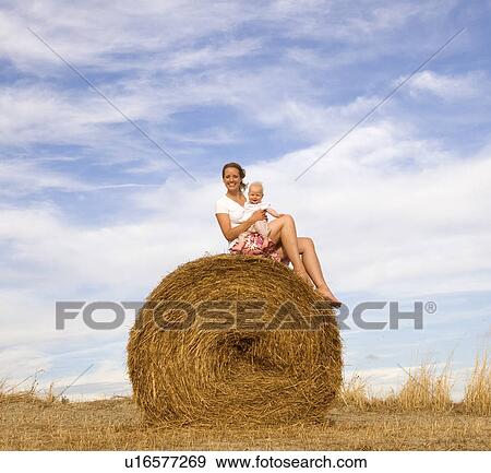woman holding baby on hay bale View Large Photo Image Stock Photo - woman holding baby on hay bale. Fotosearch