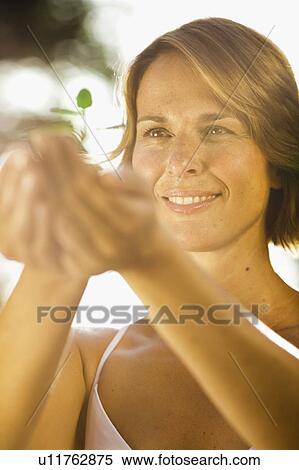 Stock Photography - woman holding sapling with both hands. Fotosearch