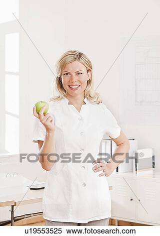 Woman in a white lab coat with an apple View Large Photo Image Stock Photography - Woman in a white lab coat with an apple. Fotosearch