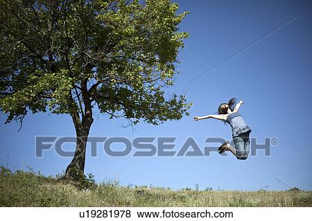 Woman jumping by tree View Large Photo Image Stock Photo - Woman jumping by tree. Fotosearch