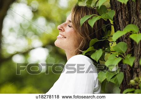 Stock Photo - woman leaning at tree. Fotosearch