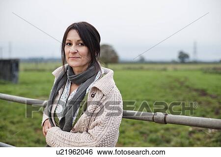 Stock Photograph - woman leaning on farm fence. Fotosearch