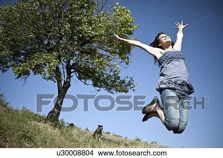 Picture - Woman leaping by tree. Fotosearch
