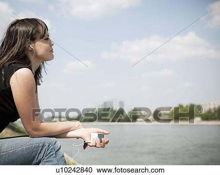 Woman listening to music by river View Large Photo Image Stock Image - Woman listening to music by river. Fotosearch
