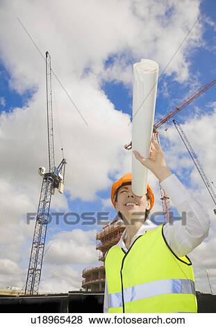 Stock Photo - Woman Looking down tube at building site. Fotosearch