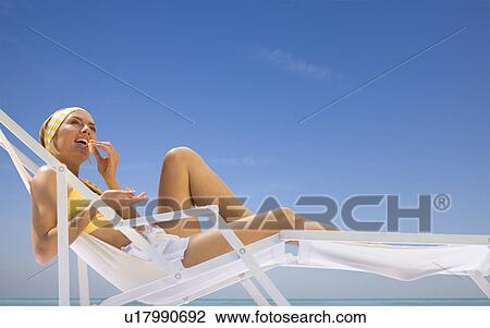 Stock Image - woman lying in a sun lounger. Fotosearch