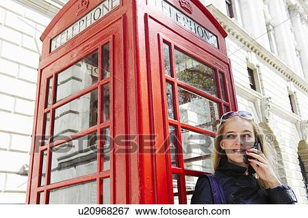 Woman next to phone booth, on her cell View Large Photo Image Stock Photo - Woman next to phone booth, on her cell. Fotosearch