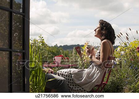 Stock Photograph - woman on balcony drinking tea. Fotosearch