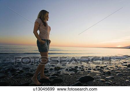 Woman on beach watching sunset low angle View Large Photo Image Stock Photo - Woman on beach watching sunset low angle. Fotosearch