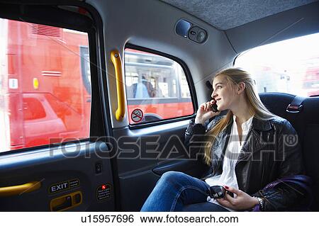 Stock Photograph - Woman on the phone, in taxi. Fotosearch