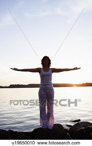 Stock Image - Woman Performing Yoga At Lakeside. Fotosearch
