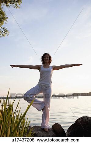 Woman Performing Yoga At Lakeside View Large Photo Image Stock Photo - Woman Performing Yoga At Lakeside. Fotosearch