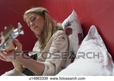 Stock Photo - woman playing guitar on bed. Fotosearch